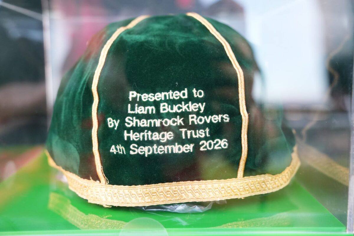 A green velvet cap with gold braid in a display case, embroidered "Presented to Liam Buckley By Shamrock Rovers Heritage Trust 4th September 2026".