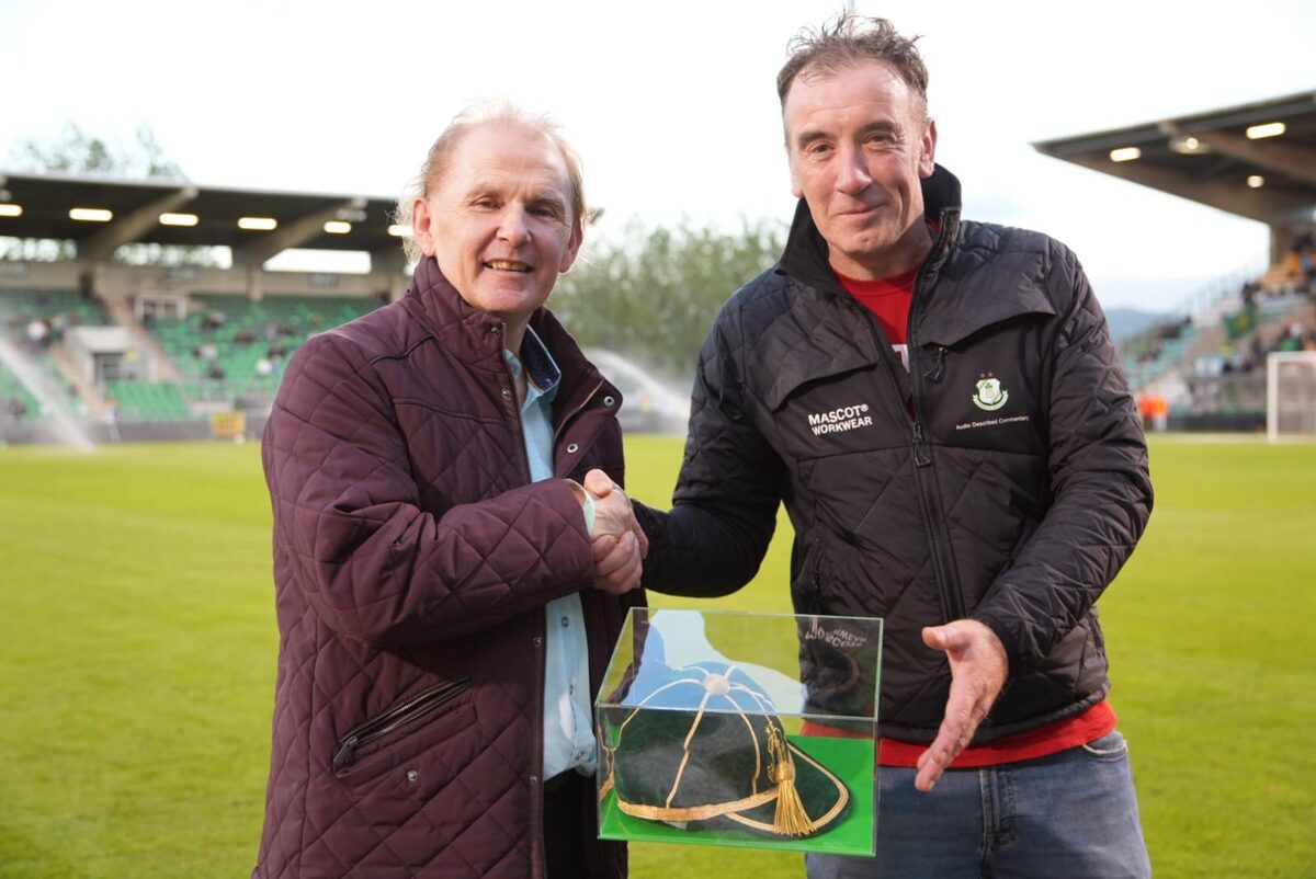 Liam Buckley shaking hands on the pitch at Tallaght Stadium while being presented with a cased green and gold cap.